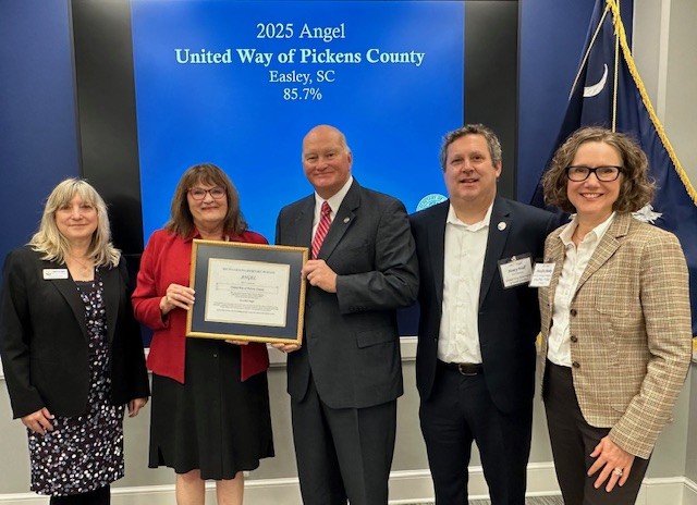 United Way staff pose with Secretary of State Mark Hammond with their Angel Award framed certificate.